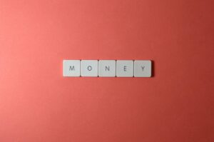 Minimalist layout showing word 'money' with letter tiles on a coral background.